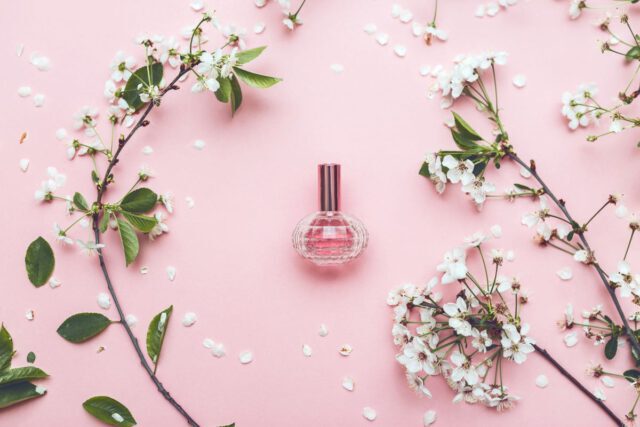 Lane perfumy na różowym tle obok kwiatów