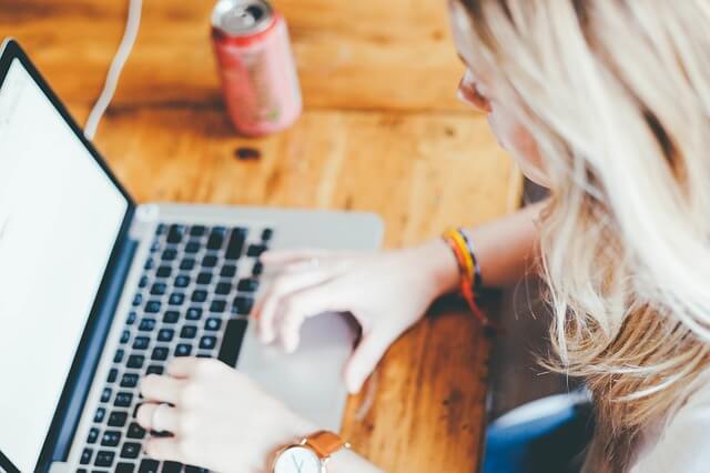 Blondwłosa kobieta pisze na laptopie